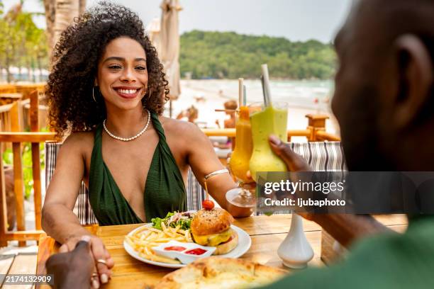 couple enjoying lunch and drinks at beachside restaurant - honeymoon stock pictures, royalty-free photos & images