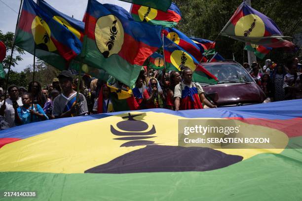 Relatives wave Kanaky flags as they attend the procession of late local resident Johan Kaidine during processions to return bodies to the Saint-Louis...