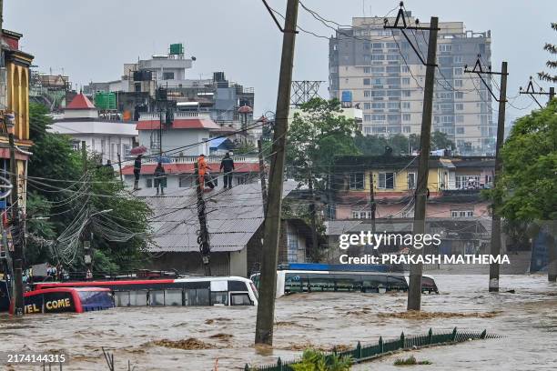 Residents climb over a rooftop as their neighbourhood submerged in flood waters after the Bagmati River overflowed following heavy monsoon rains in...