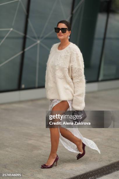 Gili Biegun wearing a cream sweater, a skirt, maroon pointed-toe heels, a handbag, sunglasses is seen outside Ermanno Scervino during the Milan...