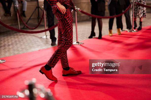 auf dem roten teppich läuft der mann in roten hosen und schuhen. - filmfestival stock-fotos und bilder