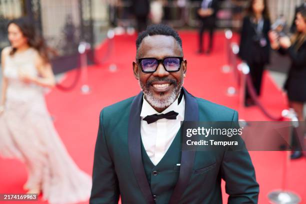 the hispanic actor poses on the red carpet, looking directly at the camera. - red carpet event stock pictures, royalty-free photos & images