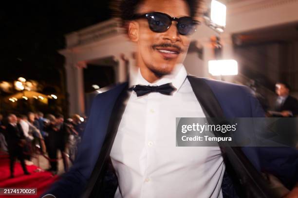 in a tuxedo, the man moves fast down the red carpet, filled with expectation and excitement. - red carpet paparazzi stock pictures, royalty-free photos & images