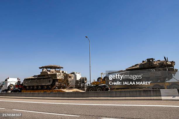 Trucks transport an Israeli army main battle tank and an infantry-fighting vehicle headed for deployment along the border with Lebanon, along a...