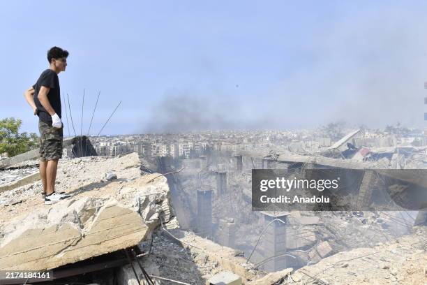 Smoke rises as damage occurred in the surrounding buildings as a boy is seen on the wreckage following Israeli warplanes targeted the Dahiyeh area in...