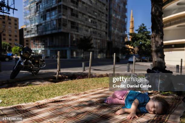 Heaven, 8-months-old, sleeps on a blanket at a park after she and her family were displaced by Israeli airstrikes on Dahieh on September 28, 2024 in...