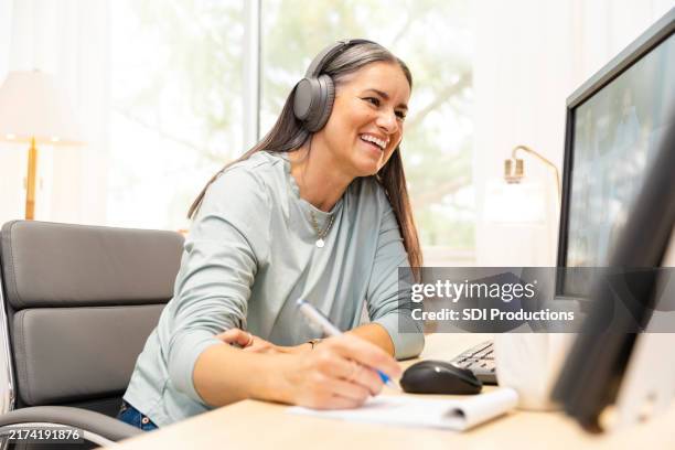 foto dal basso di manager donna matura sorridente durante l'incontro con i suoi colleghi durante una videochiamata - educazione online foto e immagini stock