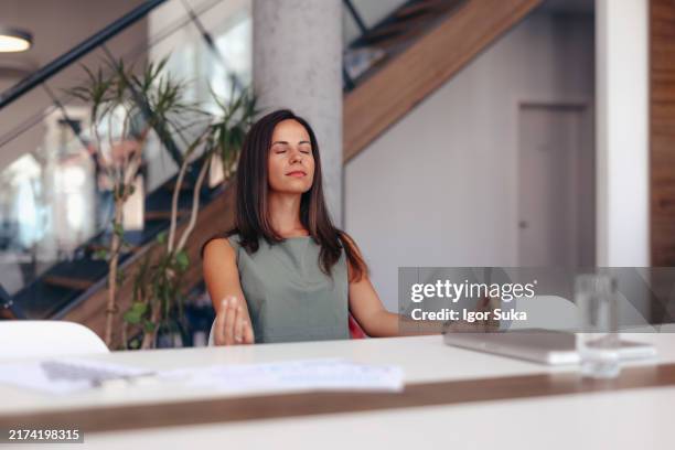 businesswoman practicing meditation at office desk for stress relief - health and wellbeing at work stock pictures, royalty-free photos & images