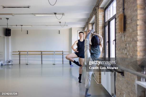 two dancers stretching and chatting at barre - ballet rehearsal stock pictures, royalty-free photos & images