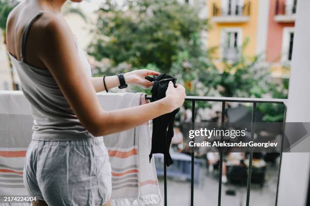 female positioning underwear on balcony to dry after washing - secar roupa imagens e fotografias de stock