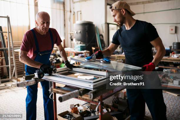 two fabrication workers assembling a window frame at workshop - pvc window stock pictures, royalty-free photos & images