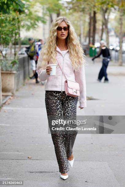 Emili Sindlev wears pink sweatshirt, pink Hermes bag, leopard print jeans, white heels, outside Ganni, during Womenswear Spring/Summer 2025 as part...