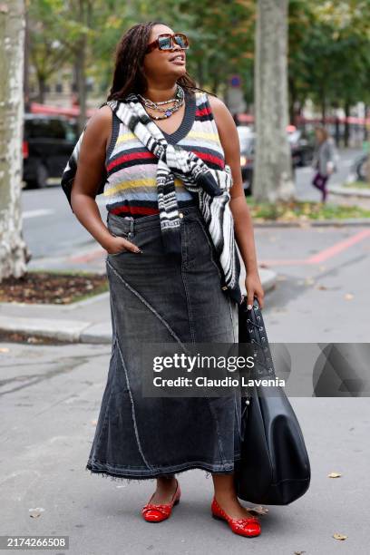 Gabriella Karefa Johnson wears striped knitted vest, grey long denim skirt, black tote bag, red ballet flats, outside Ganni, during Womenswear...