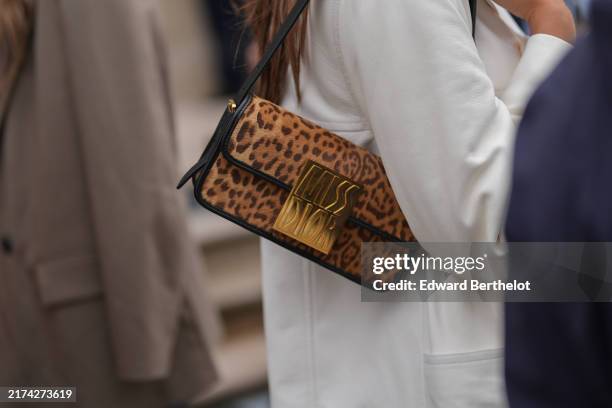 Guest wears black dark brown Leopard pattern/print Dior Miss Dior leather bag, white oversized blazer jacket, outside Dior, during the Paris Fashion...