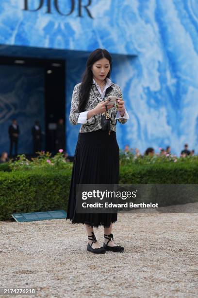 Guest wears white buttoned up long sleeve shirt, black dark gray white pattern/print cropped jacket, black pleated Dior midi skirt, black Dior saddle...