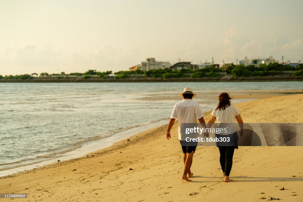 ビーチを歩く中年成人のカップル
