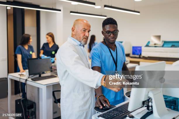 a male student listens attentively to a senior scientist, who explains how medical samples are tested in a laboratory - estudante de medicina imagens e fotografias de stock