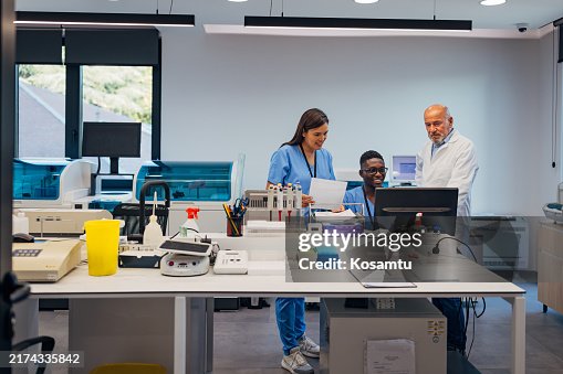 Deux étudiants en biochimie souriants discutent des résultats d’analyses biochimiques avec un biochimiste senior du laboratoire Deux étudiants en biochimie souriants discutent des résultats d’analyses biochimiques avec un biochimiste senior du laboratoire