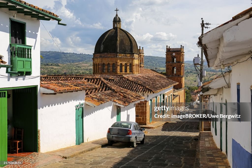 View to a street with typical traditional houses and cathedral in historic town Barichara on a sunny day, Colombia, South America