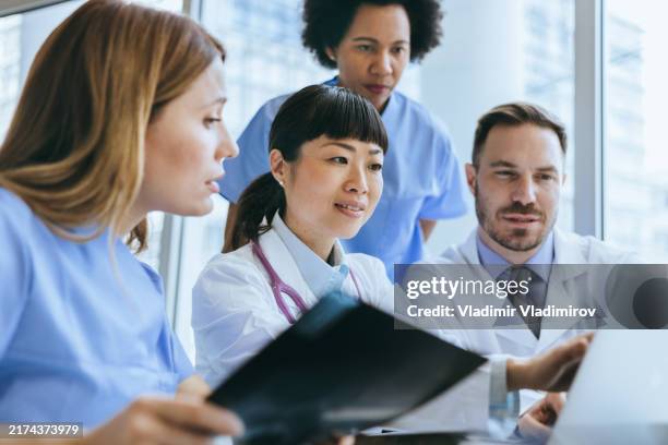 medical team discussing over a laptop - medical-round-table stock pictures, royalty-free photos & images