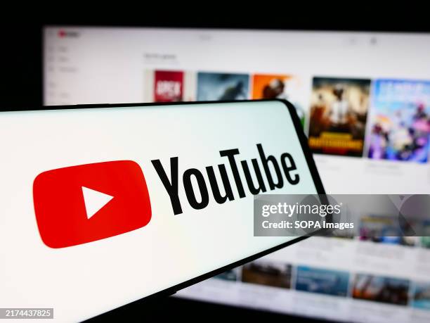 In this photo illustration, a cellphone with the logo of American online video sharing platform company YouTube is seen in front of website.