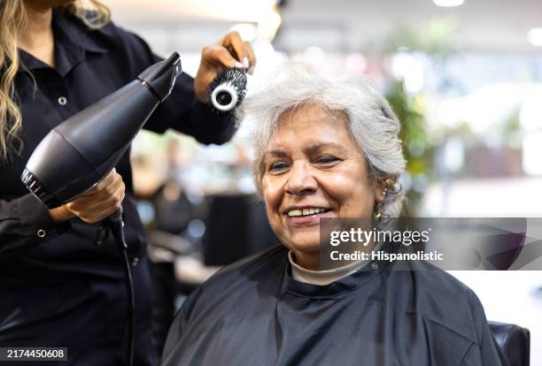 senior woman smiling at the hairdressers while getting a haircut - haar knippen stockfoto's en -beelden