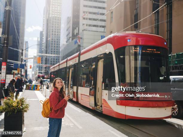 femme utilisant un smartphone attendant le tramway à toronto - toronto photos et images de collection