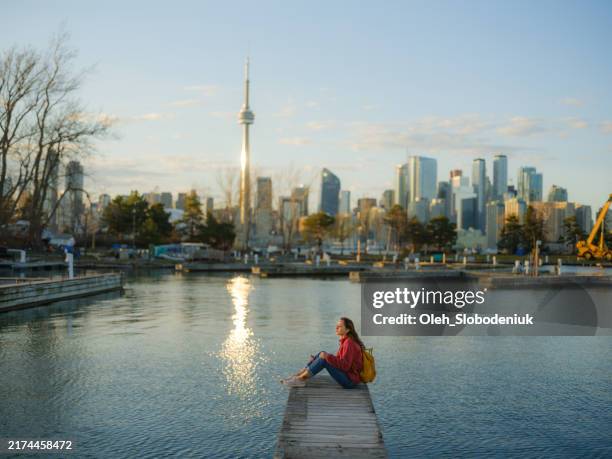 woman on the wooden pier in toronto looking at tranquil view - toronto stock-fotos und bilder