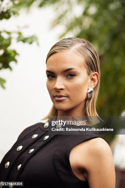 Emilia Silberg wears long black sleeveless dress with split and metal buttons outside The Paco Rabanne show during Womenswear Spring/Summer 2025 as...