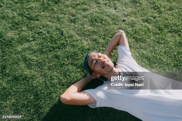 man lying on grass in summer - lying down stock pictures, royalty-free photos & images