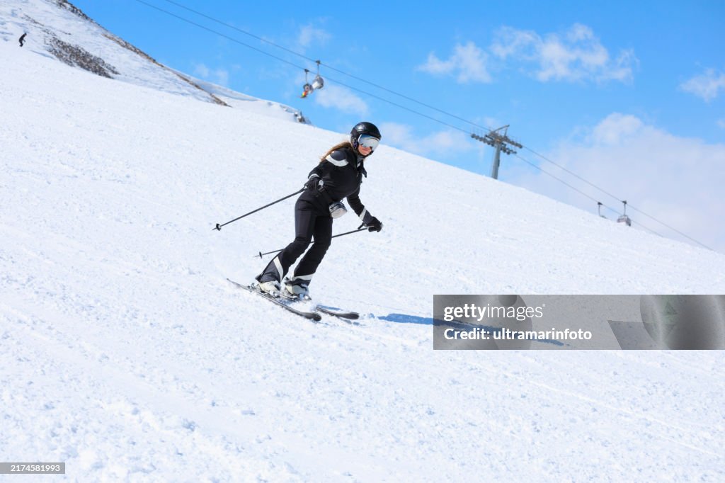 Active lifestyle, winter sport women snow skier skiing, enjoying on sunny ski resorts. Skiing carving at high speed against blue sky.