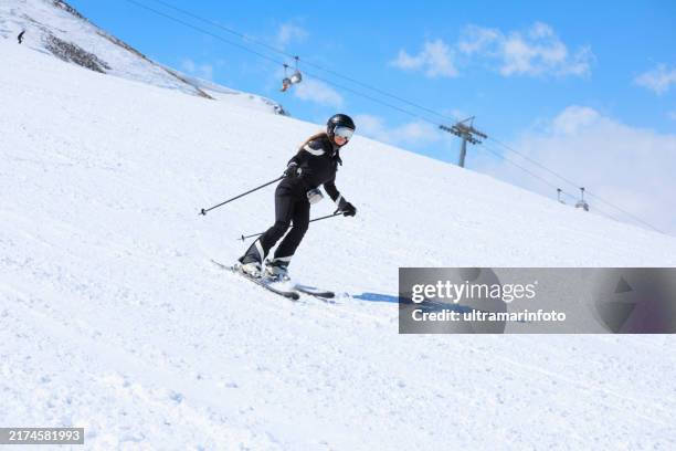 Active Lifestyle Winter Sport Women Snow Skier Skiing Enjoying On Sunny Ski Resorts Skiing Carving At High Speed Against Blue Sky High-Res Stock Photo