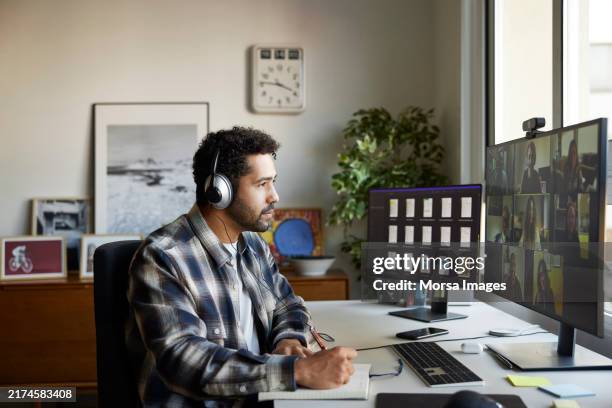 businessman writing while discussing on video call - télétravail photos et images de collection