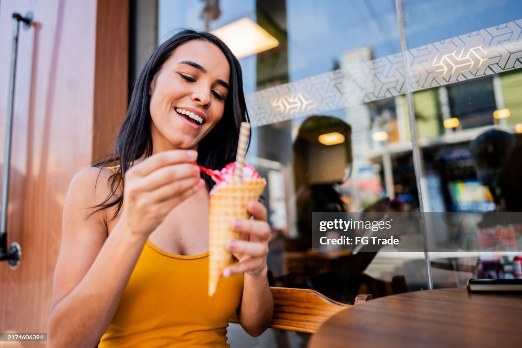 Young woman eating ice cream on an outside restaurant table