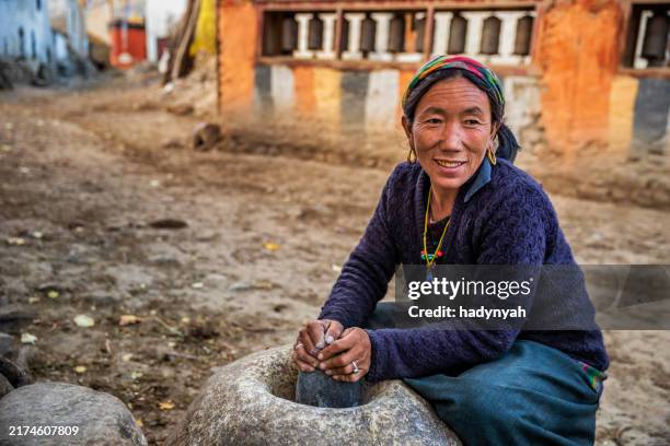 tibetan woman using a stone mortar to make flour, upper mustang, nepal - sherpa village stock pictures, royalty-free photos & images