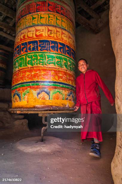 novice tibetan monk turning the prayer wheel, tsarang village, upper mustang, nepal - tibet stock pictures, royalty-free photos & images