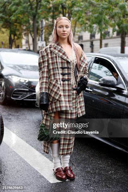 Regina Anikiy wears nude and silver sheer top, beige black and red checked wool blazer with matching midi skirt, white socks, burgundy loafers, green...