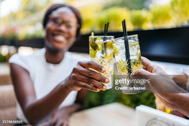 young black couple having a celebratory toast with mojitos in a bar outdoors - alcohol free stock pictures, royalty-free photos & images