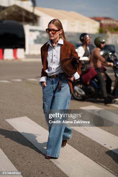 Guest wears denim wide leg jeans, a brown jacket, a bag, a blue button shirt is seen outside Prada show during the Milan Fashion Week Menswear...