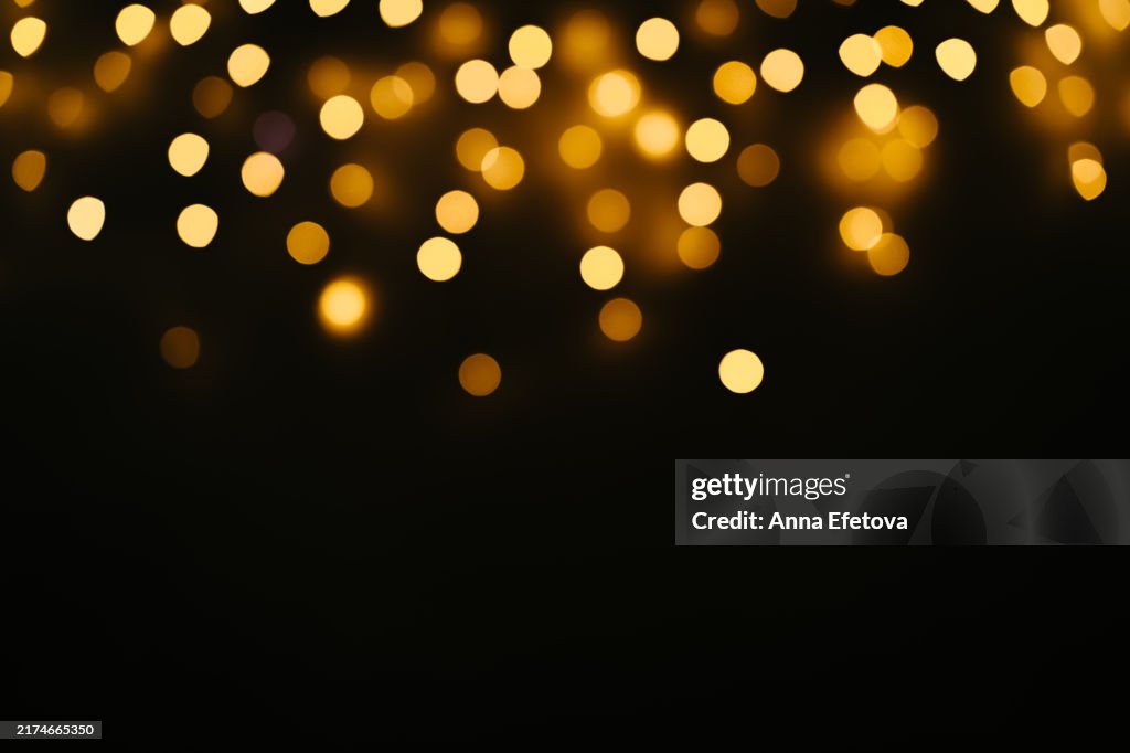 Golden Bokeh Lights set against a Dark Background perfect for Celebrations. Christmas and Happy New Year celebration concept