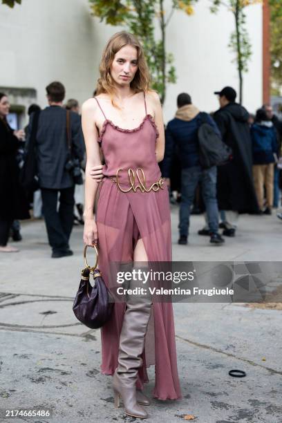 Guest wears a Chloé gold belt, a blush pink long see-trough dress, a burgundy leather bag and beige knee high heeled leather boots outside Chloé show...