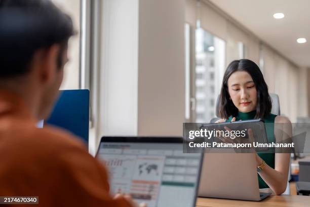 un team aziendale diversificato utilizza l'analisi dei dati per prevedere le tendenze del mercato durante una riunione strategica in un ufficio moderno. i membri del team collaborano, utilizzando laptop e display digitali per analizzare i fattori chiave ch - gestione delle relazioni con i clienti foto e immagini stock