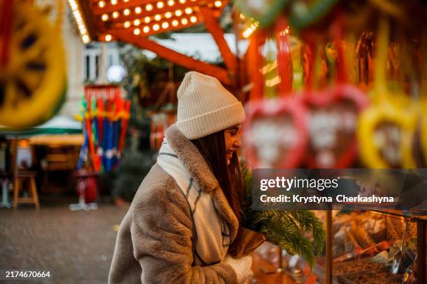 happy young woman of european appearance at christmas market in germany. festive city. decor. new year. winter holidays. - mercado de natal imagens e fotografias de stock