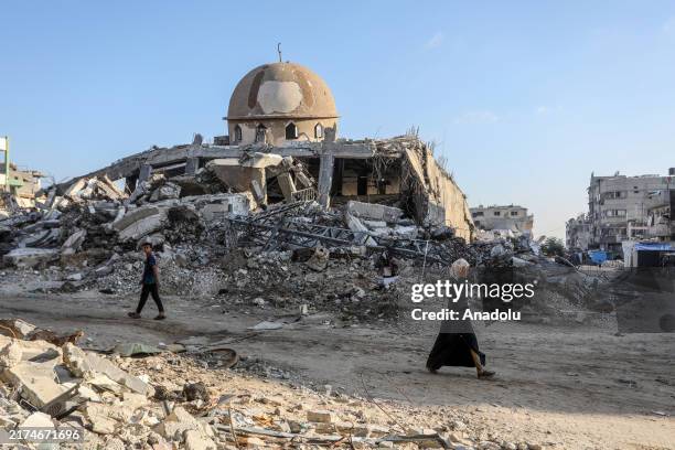 Palestinians walk near debris of destroyed buildings as the scale of destruction, caused by Israeli attacks, comes to surface following the...