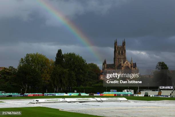 Members of the ground staff pull the rain covers onto the field backdropped by a rainbow and Worcester Cathedral as play is abandoned due to rain...