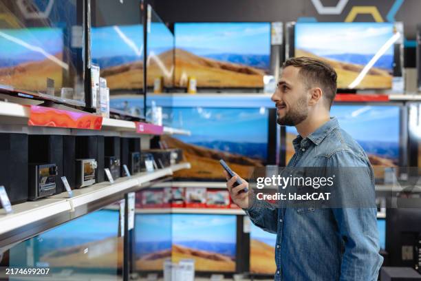 hombre comprando un nuevo televisor en una tienda de electrónica - ir de compras fotografías e imágenes de stock