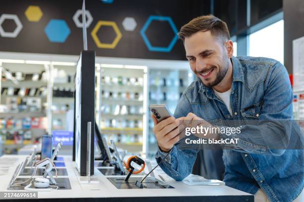 man shopping for a new smartphone in an electronics store - electronics store stock pictures, royalty-free photos & images