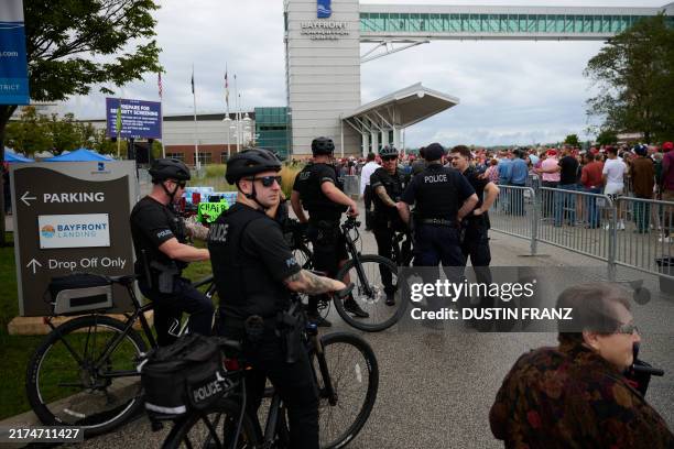 Police and security officials keep watch as supporters line up hours before the start of a campaign rally for former US President and Republican...