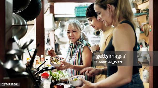 seniorin bringt touristen in der küche thailändisches kochen bei - thailändische küche stock-fotos und bilder