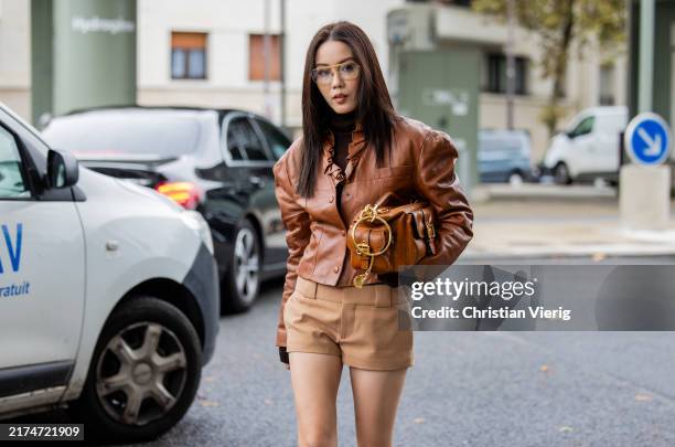 Jenny Tsang wears brown oversized leather jacket, beige shorts, bag outside Chloe during Womenswear Spring/Summer 2025 as part of Paris Fashion Week...